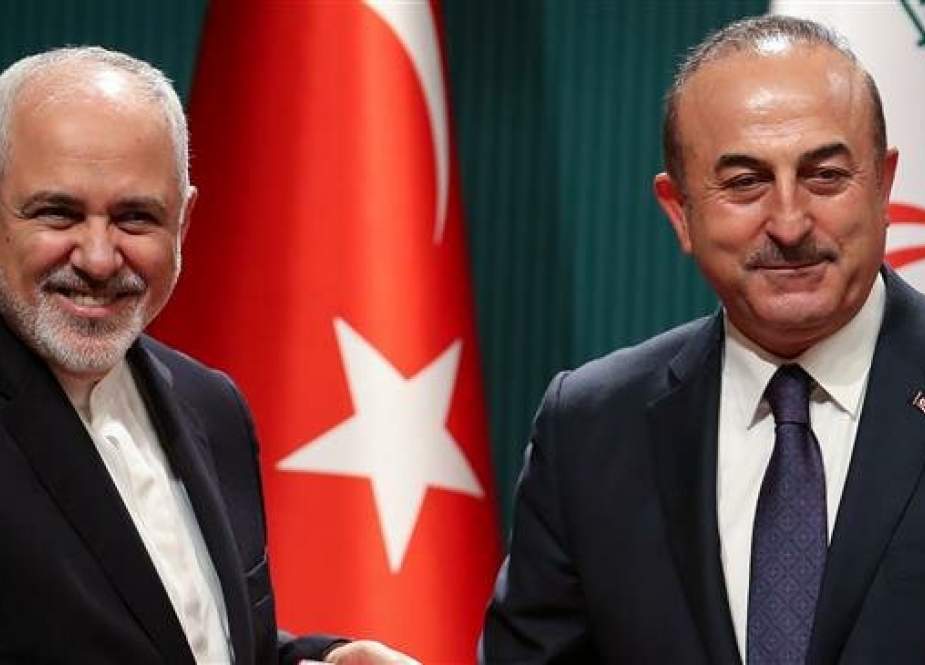 Iranian Foreign Minister Javad Zarif (L) and Turkish Foreign Minister Mevlut Cavusoglu (R) pose for a photo after signing a cooperation agreement before a joint press conference. (Photo by AFP)