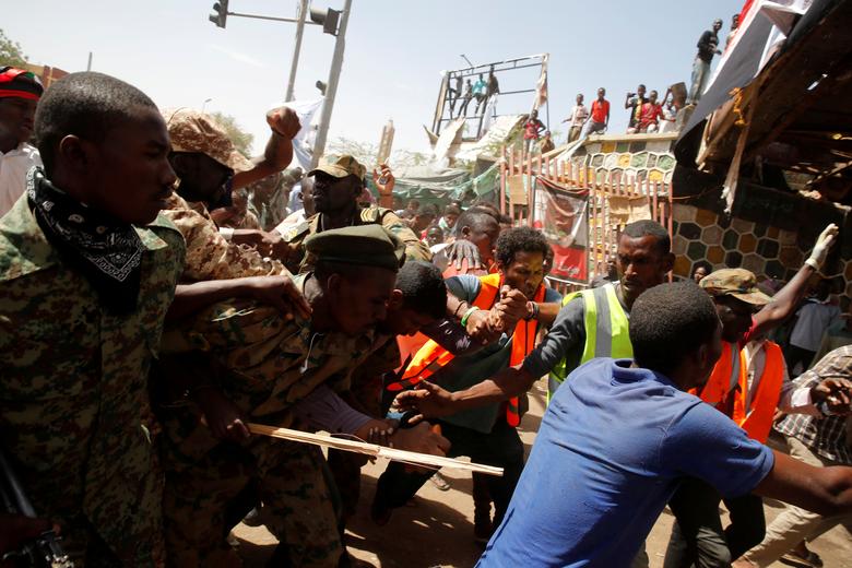 Sudanese demonstrators try to beat a man who they think is a government agent, as soldiers try to take him out of the crowd in Khartoum, Sudan April 16, 2019