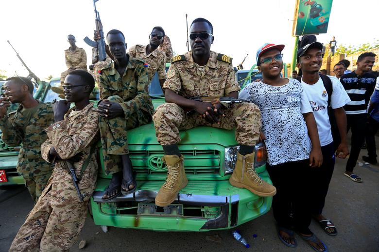 Sudanese boys pose for a photo with Sudanese military personnel, positioned near a bridge gate, during a sit-in protest outside the Defence Ministry in Khartoum, April 15