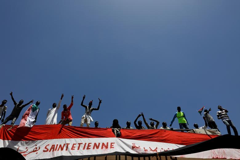 Sudanese demonstrators protest as they stand on a railway bridge near the Defence Ministry in Khartoum, April 15