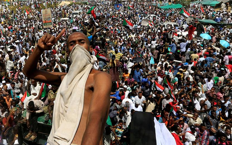 A Sudanese demonstrator gestures while riding atop a military truck as he protests against the army's announcement that President Omar al-Bashir would be replaced by a military-led transitional council, near the Defense Ministry in Khartoum, April 12