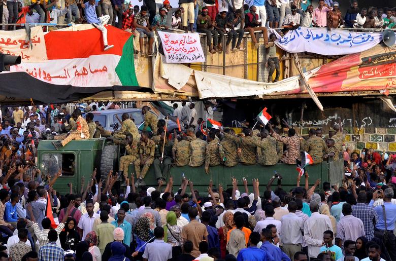 A Sudanese military truck passes through demonstrators attending a sit-in protest outside the Defense Ministry in Khartoum, April 14