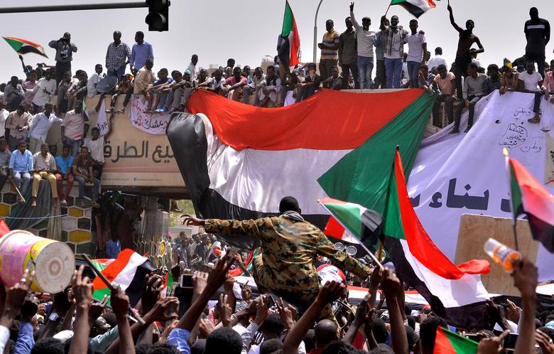 A military officer is carried by the crowd as demonstrators chant slogans and carry their national flags, after Sudan's Defense Minister Awad Mohamed Ahmed Ibn Auf said that President Omar al-Bashir had been detained 
