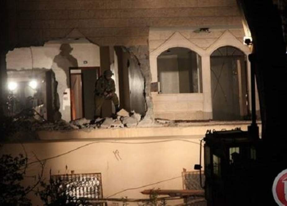 Israeli soldier is busy demolishing a family apartment of Palestinian.jpg
