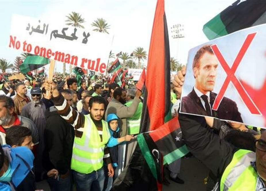 Libyans wave the national flag and carry a portrait of French President Emmanuel Macron during a demonstration against strongman Khalifa Haftar in the capital Tripoli