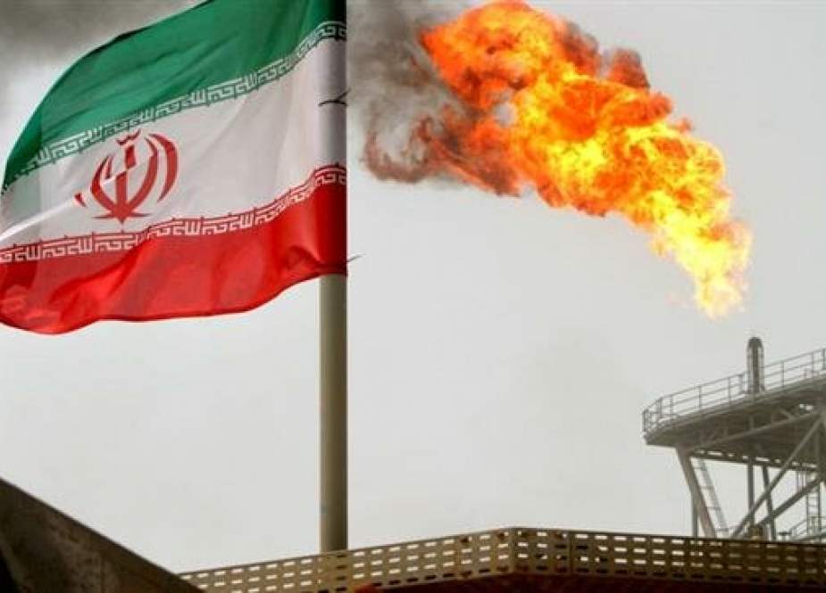 A gas flare on an oil production platform in the Soroush oil fields is seen alongside an Iranian flag in the Persian Gulf, Iran, July 25, 2005. (By Reuters)