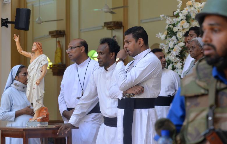 Catholic priests stand inside the church after a bomb blast in Negombo, April 21