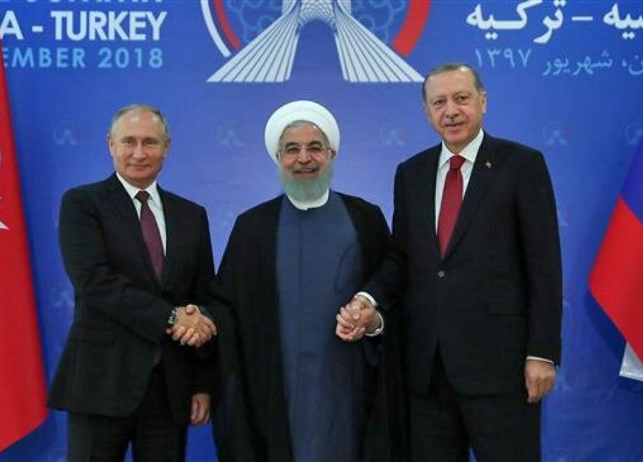 A handout picture provided by the office of Iranian President Hassan Rouhani (C) shows him holding hands with Turkish President Recep Tayyip Erodgan (R) and Russian President Vladimir Putin (L) in Tehran on September 7, 2018, as Iran hosted a summit on the Syrian conflict. (Photo by AFP)