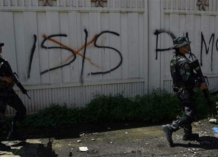Soldiers walk past graffiti promoting Daesh in the Filipino city of Marawi, on May 31, 2017. (File photo by AFP)