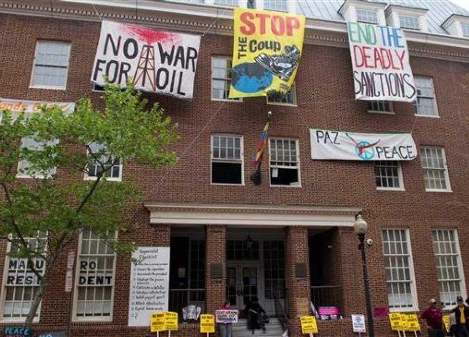 Protestors demonstrating against supporters of Venezuelan opposition leader Juan Guaido hang signs outside the Venezuelan Embassy in Washington, DC, April 25, 2019. (Photo by AFP)