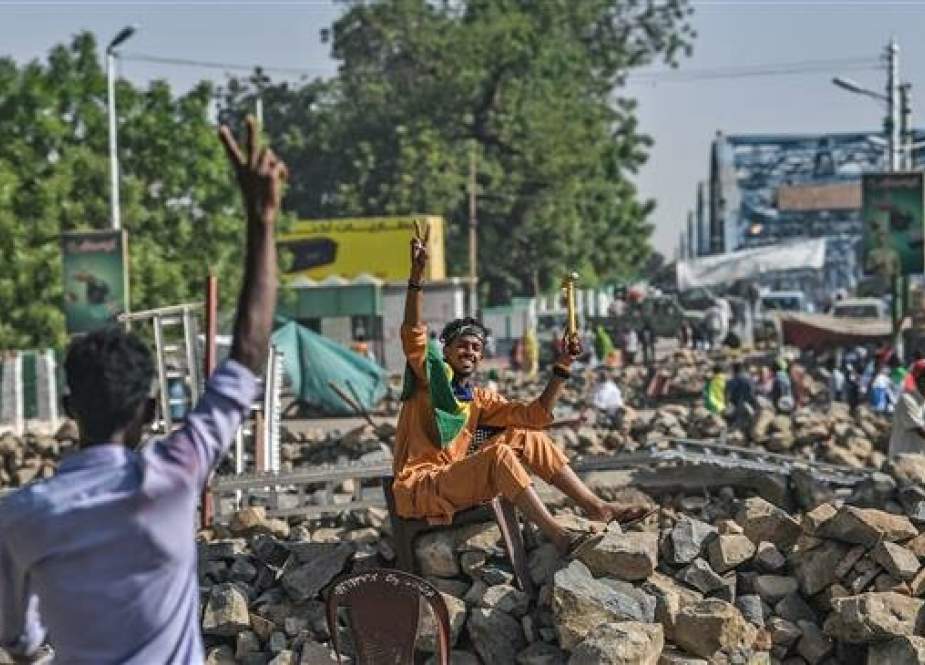 Sudanese protesters flash the V for victory sign as they man a makeshift barricade during a sit-in outside the army headquarters in the capital Khartoum on April 30, 2019. (Photo by AFP)