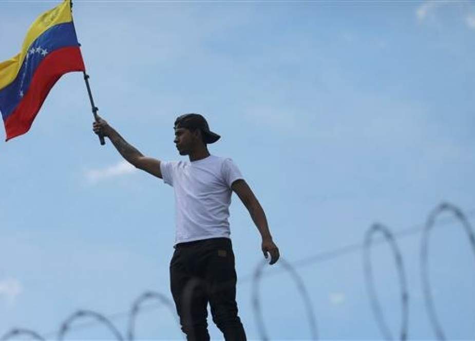 A man holds a Venezuelan flag on the roof of the Consulate of Venezuela, during a protest in Bogota, Colombia April 30, 2019. (Photo by Reuters)