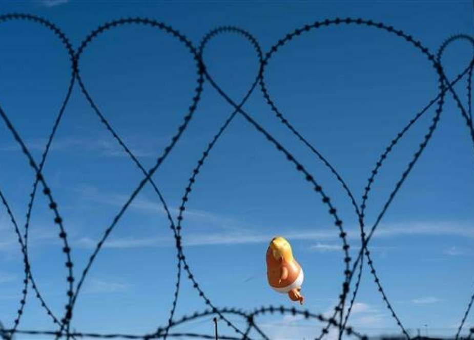 A satirical balloon of a baby US President Donald Trump is seen through the US-Mexico border fence during a demonstration against him prior to his visit to Calexico, California, as seen from Mexicali, Baja California state, Mexico, on April 5, 2019. (AFP photo)
