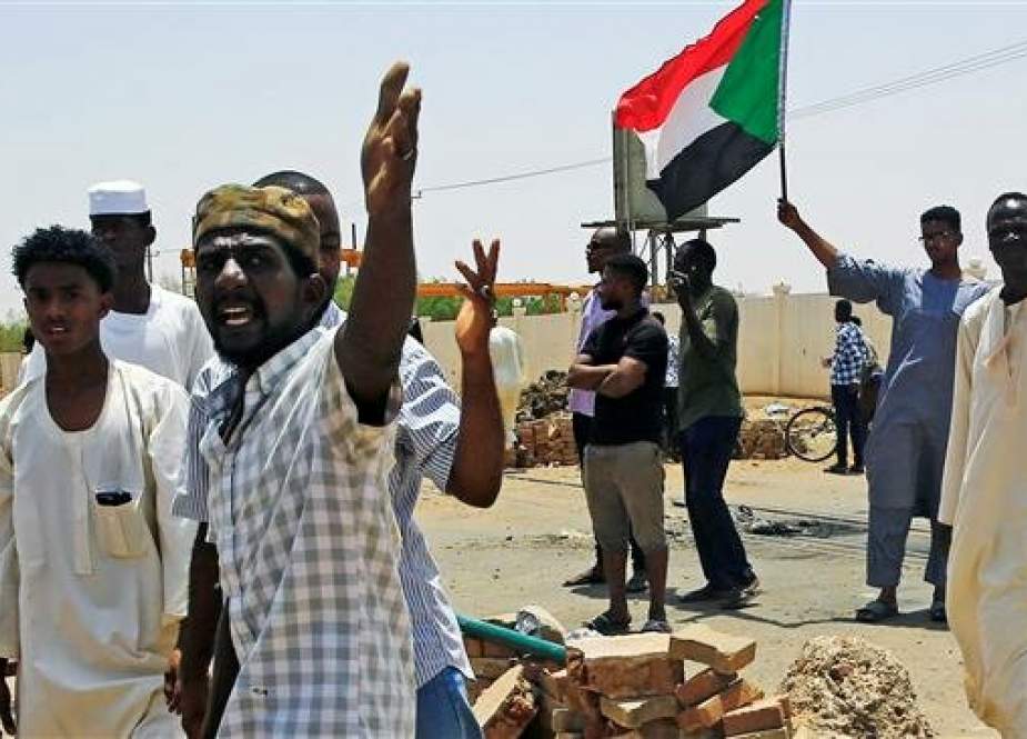 Sudanese protesters set up a barricade on a street, demanding that the country