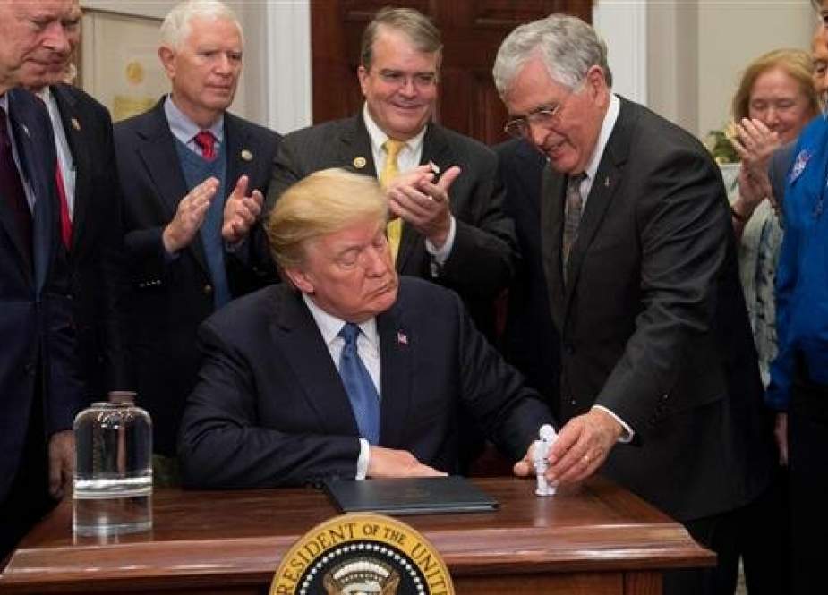 US President Donald Trump looks at an astronaut toy alongside former US Senator and Apollo 17 Astronaut Jack Schmitt (2nd R), and NASA Astronaut Peggy Whitson (R) after a signing ceremony for Space Policy Directive 1, with the aim of returning Americans to the Moon, in the Roosevelt Room at the White House in Washington, DC, on December 11, 2017. (Photo by AFP)
