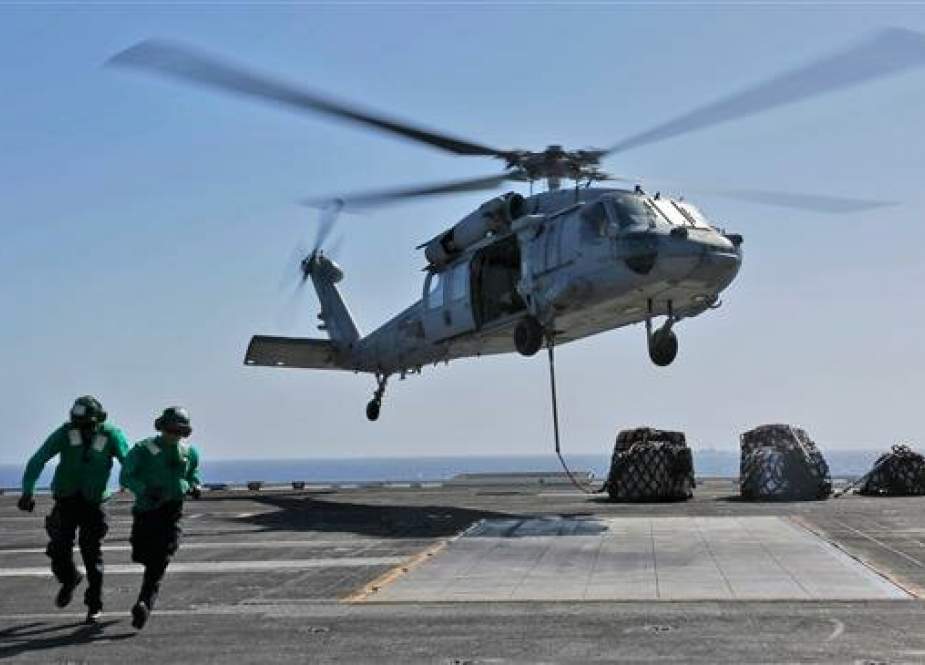 This handout picture, released by the US Navy on May 10, 2019, shows naval logistics specialists running away after attaching cargo to an MH-60S Sea Hawk helicopter on the flight deck of the Nimitz-class aircraft carrier USS Abraham Lincoln (CVN 72). (Via AFP)