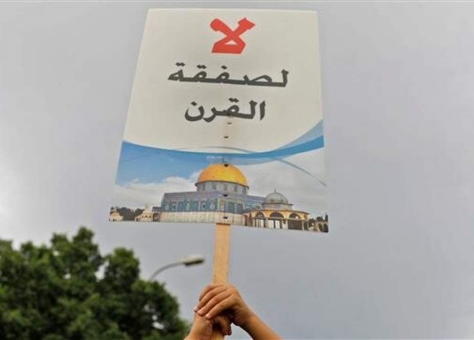 A file photo shows a Palestinian protester holding up a sign reading “No to the deal of the century.”