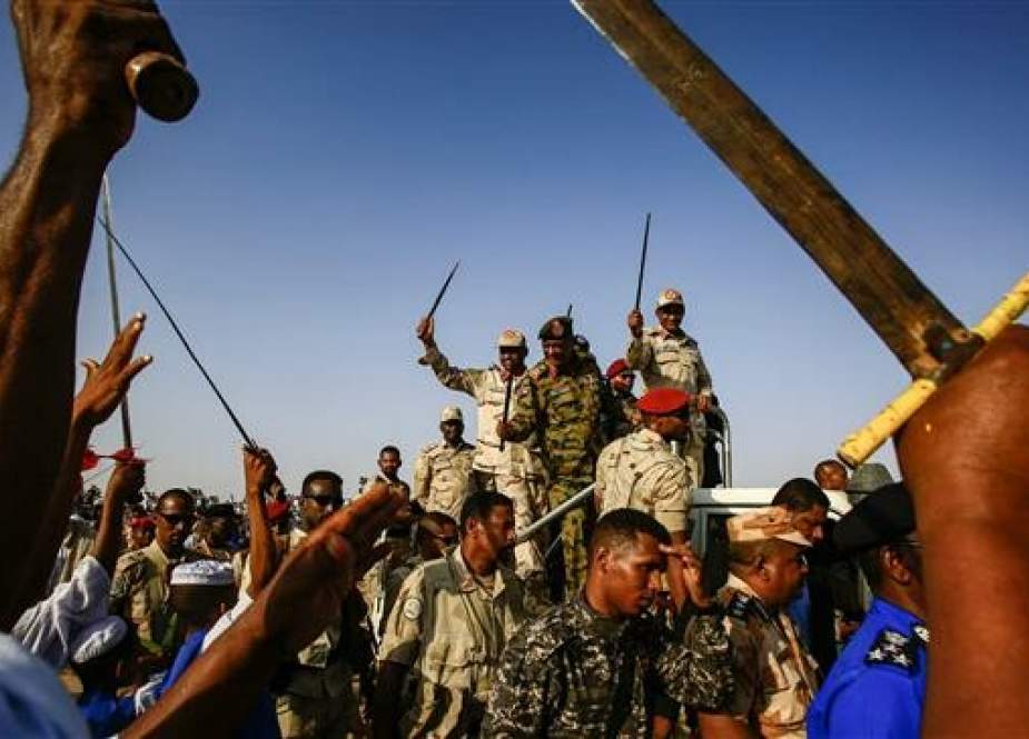 Mohamed Hamdan Dagalo (C-R), also known as Himediti, the deputy head of Sudan’s ruling Transitional Military Council (TMC) and commander of the Rapid Support Forces (RSF) paramilitaries, waves a baton as he rides in the back of a vehicle surrounded by RSF members and crowds of supporters in the village of Qarri, about 90 km north of Khartoum, on June 15, 2019. (Photo by AFP)