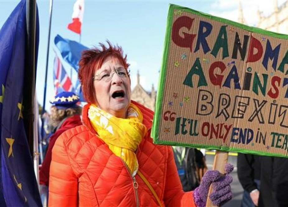 An anti-Brexit campaigner holds up a "Grandmas against Brexit" placard as she protests outside the Houses of Parliament in London on March 25, 2019. (AFP photo)