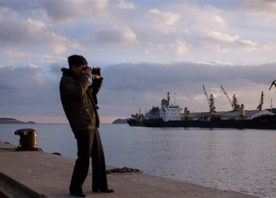 In photo taken on November 20, 2017, a man takes photos of coal and ships docked in Rajin port, near North Korea