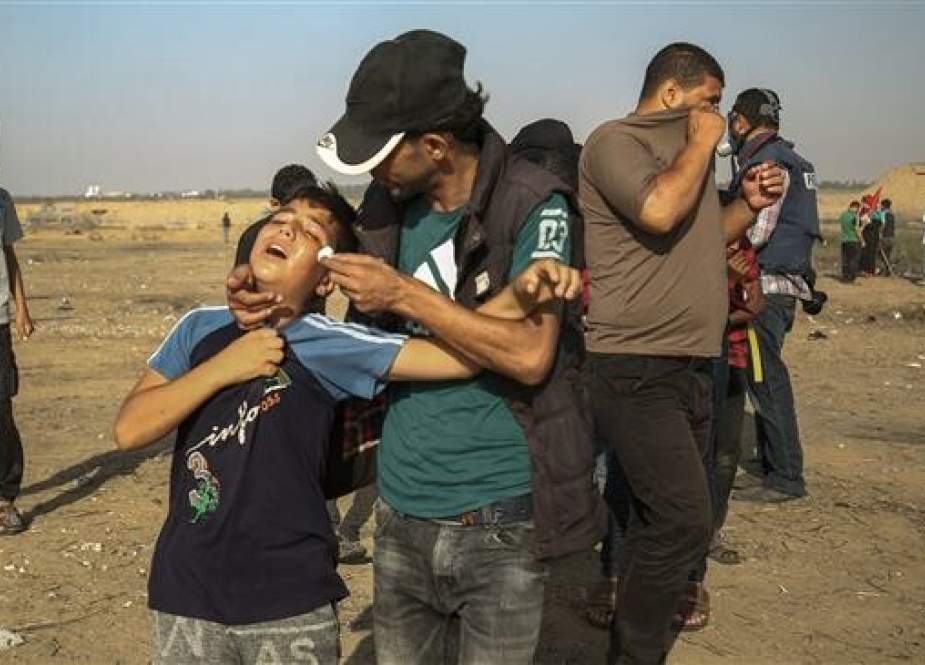 A Palestinian man aids a boy suffering from the effects of tear gas fired by Israeli forces during protests along the border fence separating Gaza from the Israeli-occupied territories east of Khan Yunis on June 21, 2019. (Photo by AFP)
