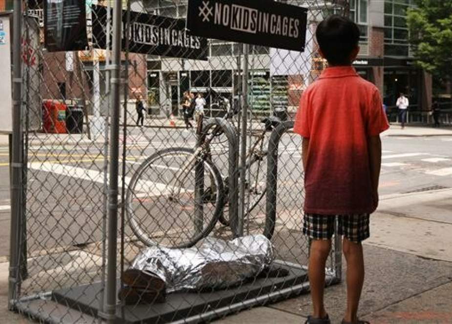 A child stands in front of a pop-up art installation depicting small children curled up underneath foil survival blankets in chain-link cages on June 12, 2019 in New York City. (AFP photos)