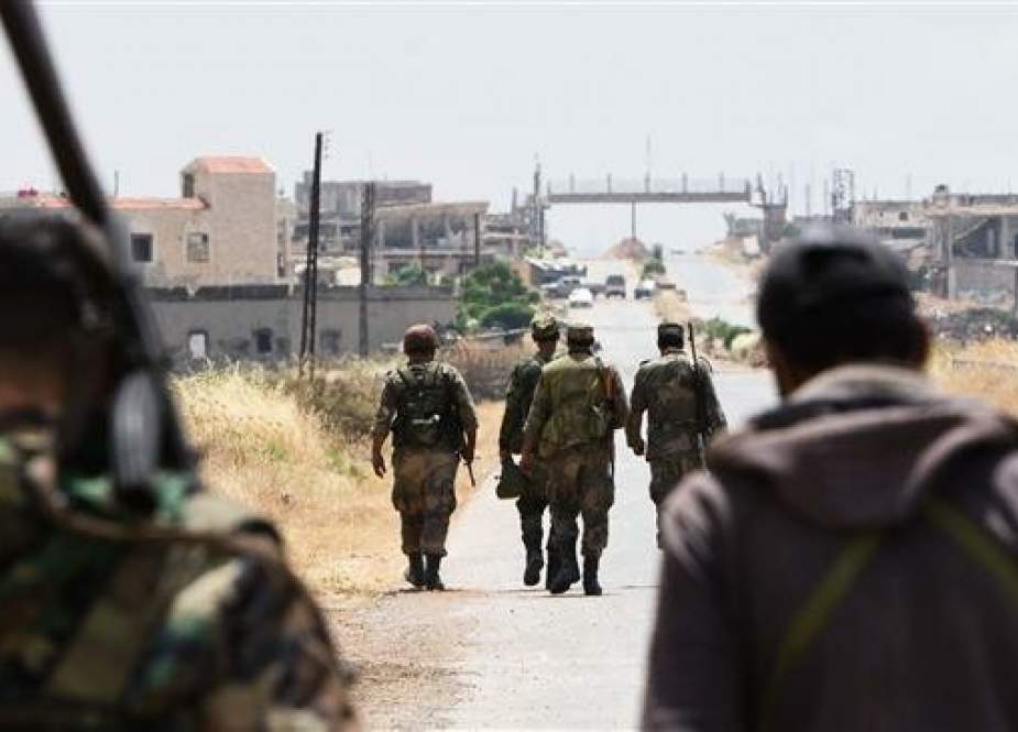 Fighters with the Syrian government forces walk on a road leading to the town of Jalamah in Syria.jpg
