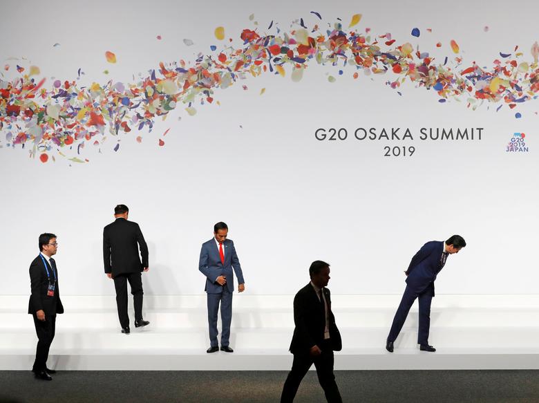 Japanese Prime Minister Shinzo Abe (L) and Indonesian President Joko Widodo (C) check their positions as they prepare for family photo session at the G20 leaders summit in Osaka, Japan, June 28