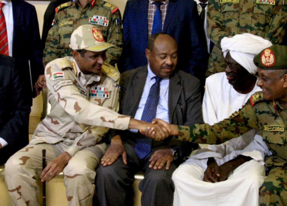 Mohamed al-Hacen Lebatt (left), AU envoy to Sudan, sits beside General Mohamed Hamdan Dagalo as he shakes hands with an army general following a press conference in Khartoum [Ebrahim Hamid/ AFP]