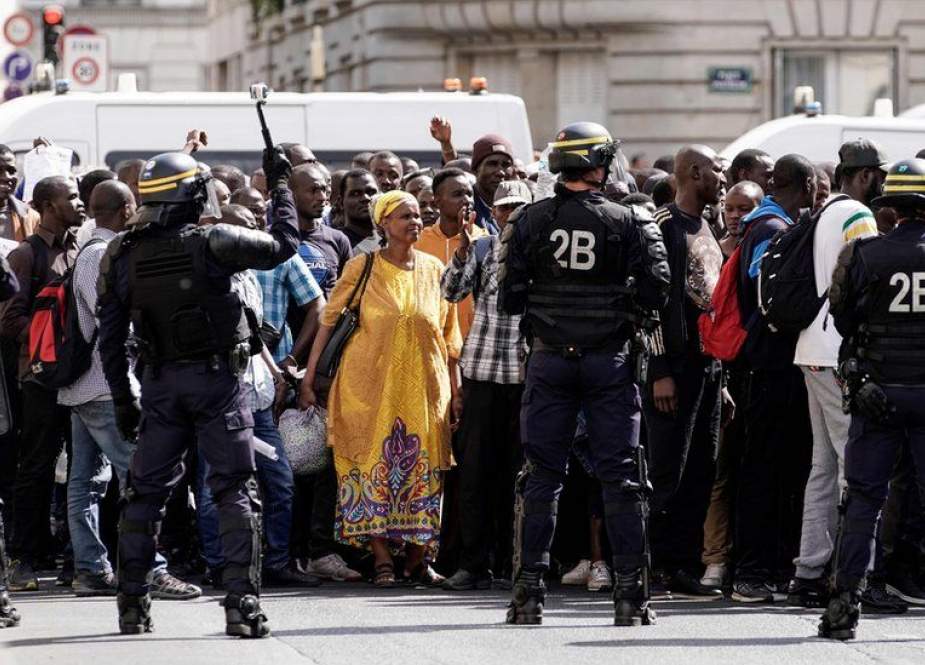 French police officers stand as undocumented migrants demonstrate to ask for the regularization of their situation near the Pantheon in Paris, on July 12, 2019.