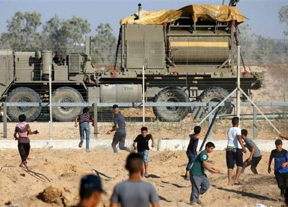 Israeli military vehicle carrying tanks of skunk water across a barbed-wire fence, near Rafah, in the southern Gaza Strip.jpg