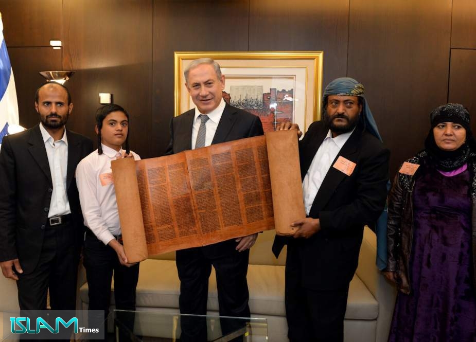Israeli Prime Minister Benjamin Netanyahu holds a 500 hundred-year-old Torah scroll as he poses with some Yemeni Jews brought to Israel, at the Knesset