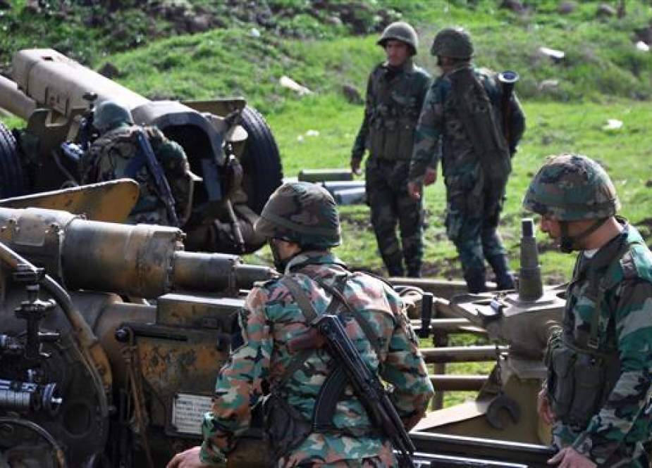 Syrian soldiers stand near an artillery gun.jpg