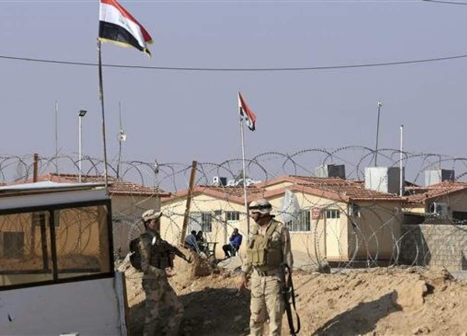 Iraqi soldiers stand guard with their weapons on the border crossing with Syria, in al-Qa