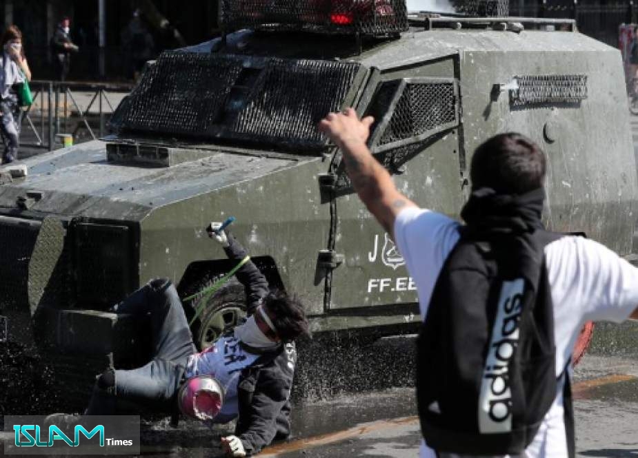 Others react as a demonstrator is run over by a riot police vehicle during a protest against Chile