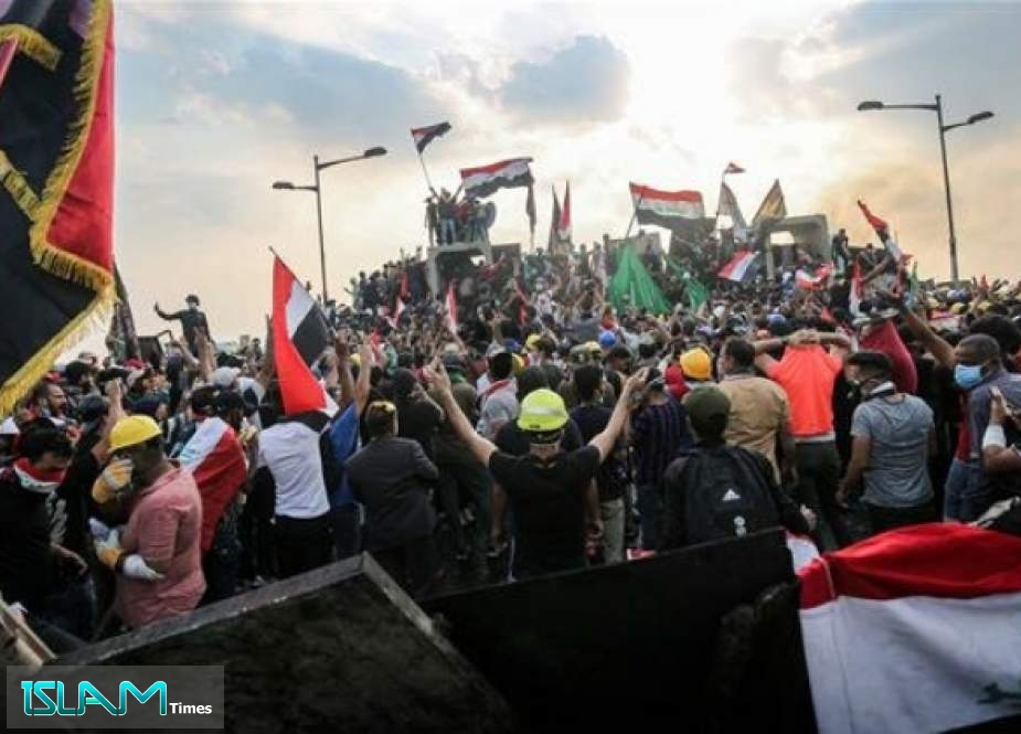 Iraqi protesters wave national flags as they stand atop concrete barriers across Baghdad