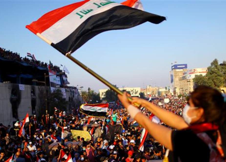 Iraqi demonstrator waves a national flag during anti-government protest, in Baghdad.jpg