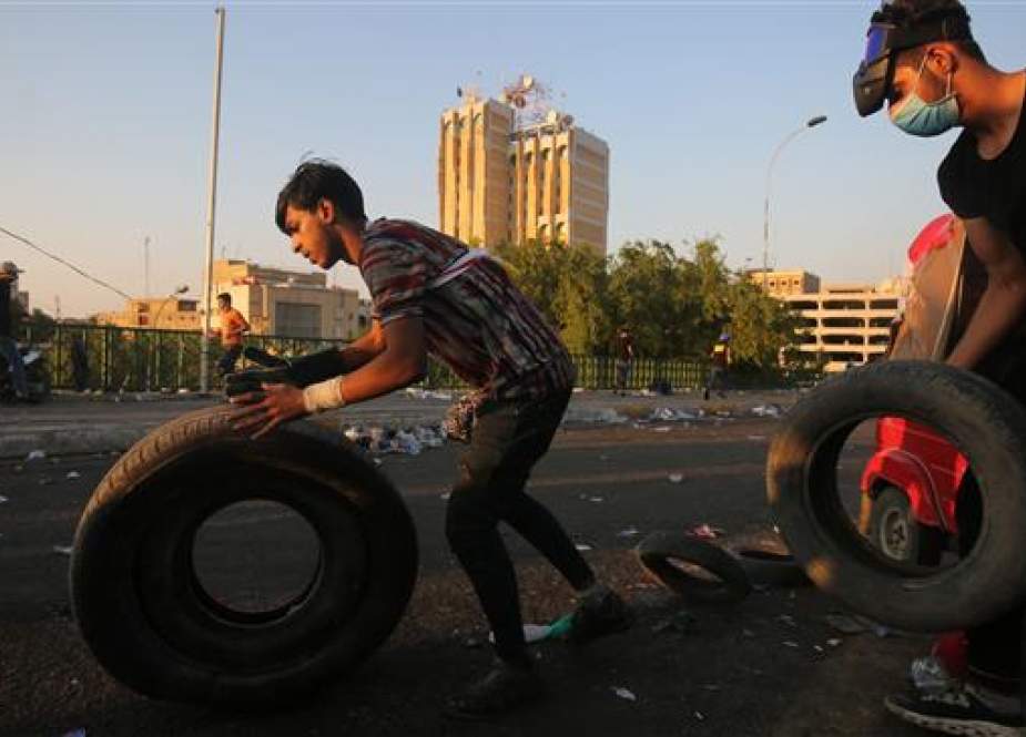 Iraqi protesters push tires to be burned.jpg