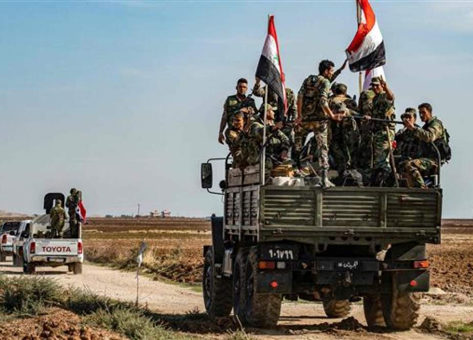 Syrian government soldiers ride in the back of a truck with national flags.jpg