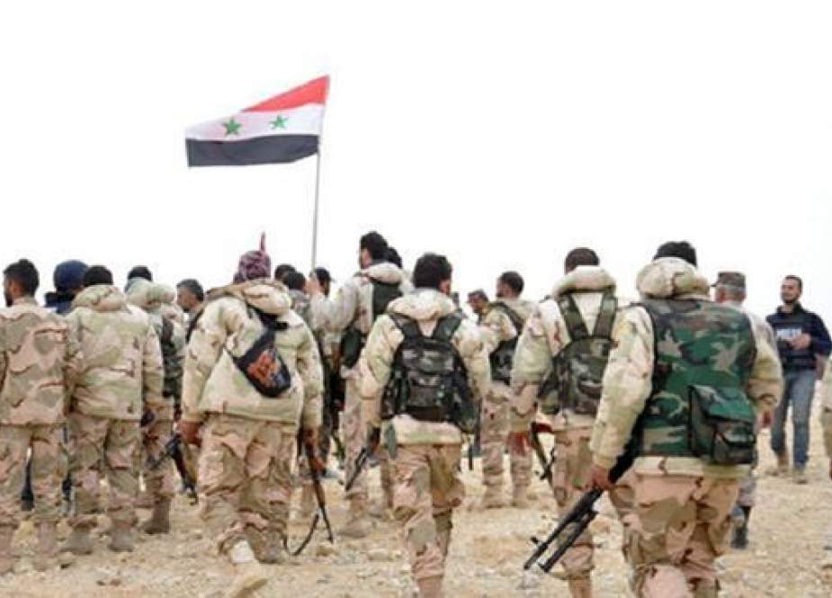 Syrian soldiers gather around a national flag.jpg
