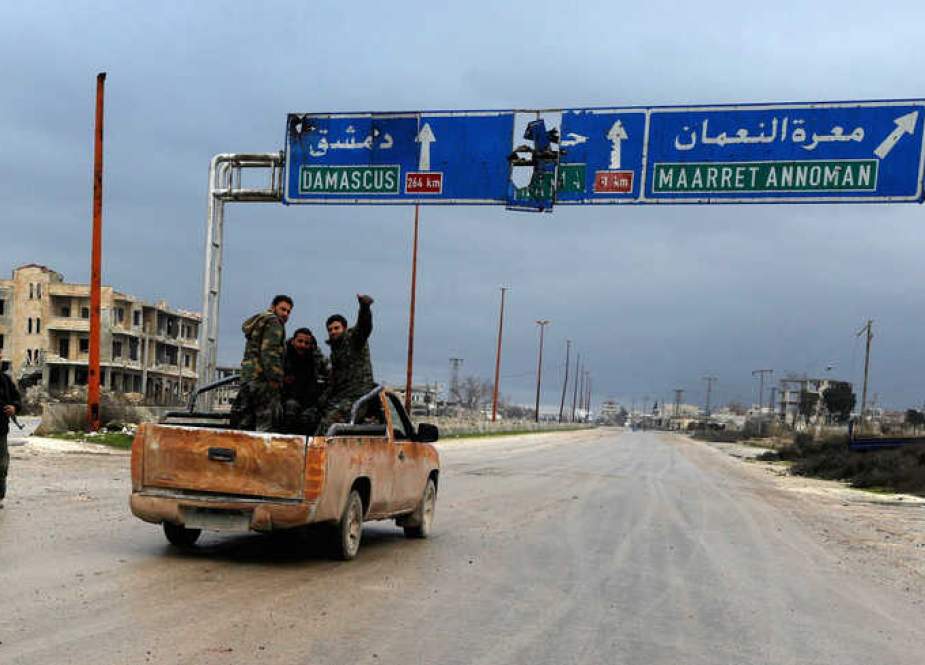 Syrian Army soldiers gesture on the highway outside Maarat al-Noaman.jpg