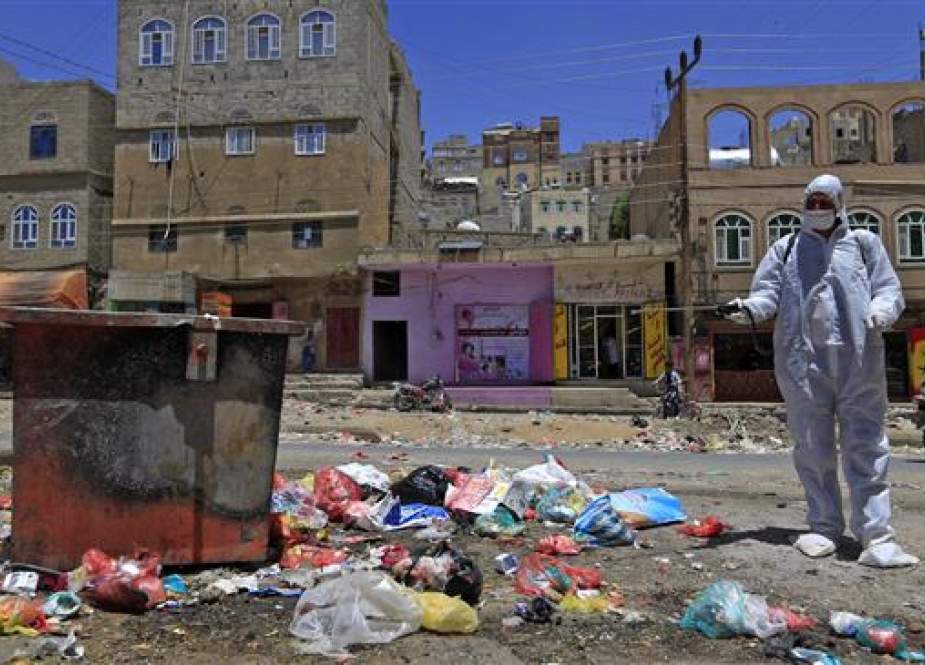 Yemeni volunteer sprays disinfectant over garbage in the one of Sana