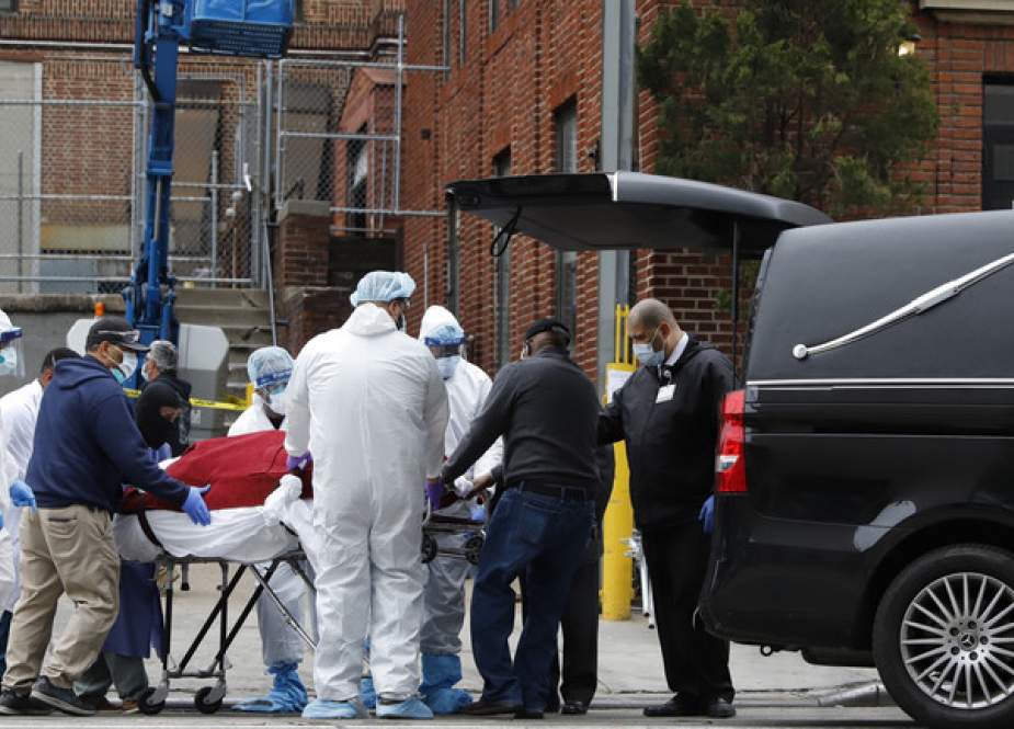 Workers load the body of a deceased person into a hearse outside a Brooklyn hospital.JPG