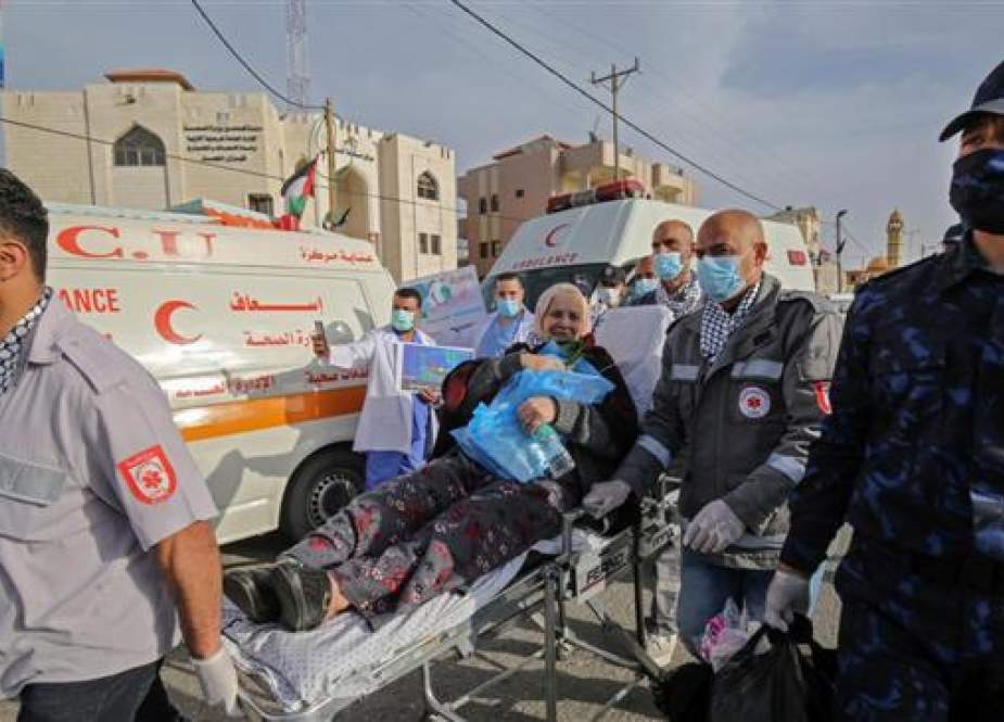 Palestinian medics escort a woman leaving the Muscat Medical Center in Khan Younis.jpg
