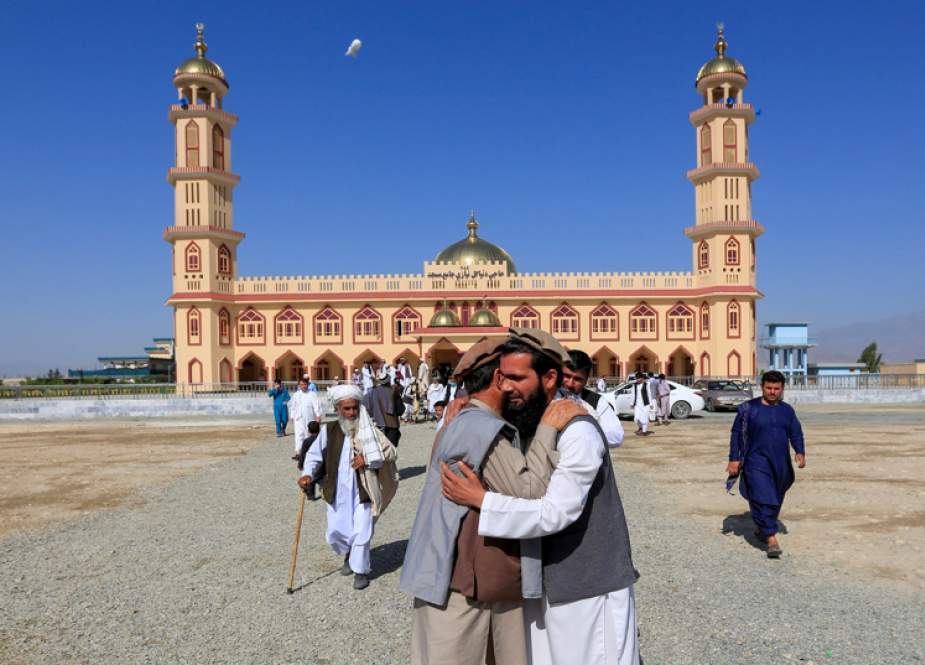 Afghan men greet each other outside a mosque after prayers on Eid al-Fitr.jpg