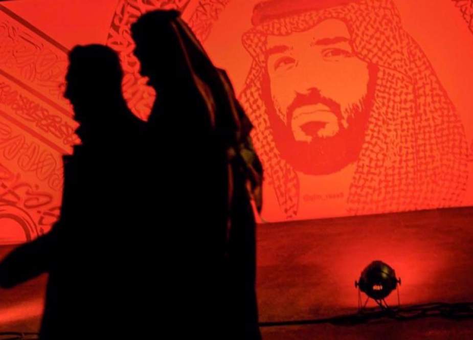 Saudis walk by a portrait of Crown Prince Mohammed bin Salman in Riyadh.jpg