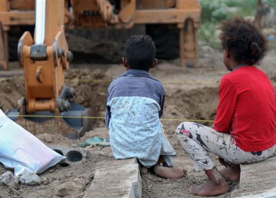 Yemeni children watch as an excavator digs graves at a specific plot for COVID-19 victims.jpg