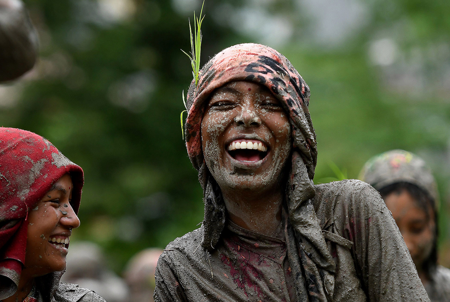 A woman smiles in a rice paddy field during National Paddy Day—marking the start of the annual rice planting season—in Tokha village on the outskirts of Kathmandu, Nepal, on June 29