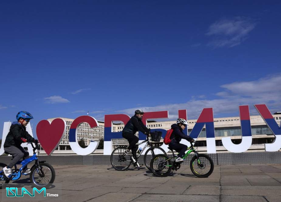 A family cycles past a sign reading, “I love Serbia,” in Belgrade, Serbia, February 15, 2022.