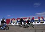 A family cycles past a sign reading, “I love Serbia,” in Belgrade, Serbia, February 15, 2022.